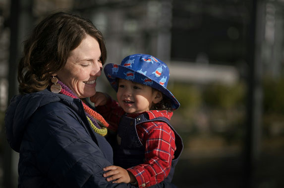 A young mother and her baby laugh in the sunshine