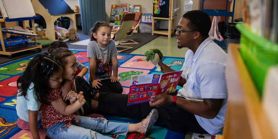 Therapist Spencer Mattox reads a book to students during a small group therapy session