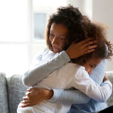 A mother hugs her child on a couch