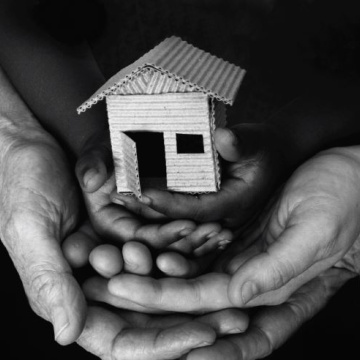 Hands holding a small cardboard house