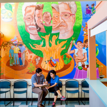 Doctor and patient in front of mural at a community health center